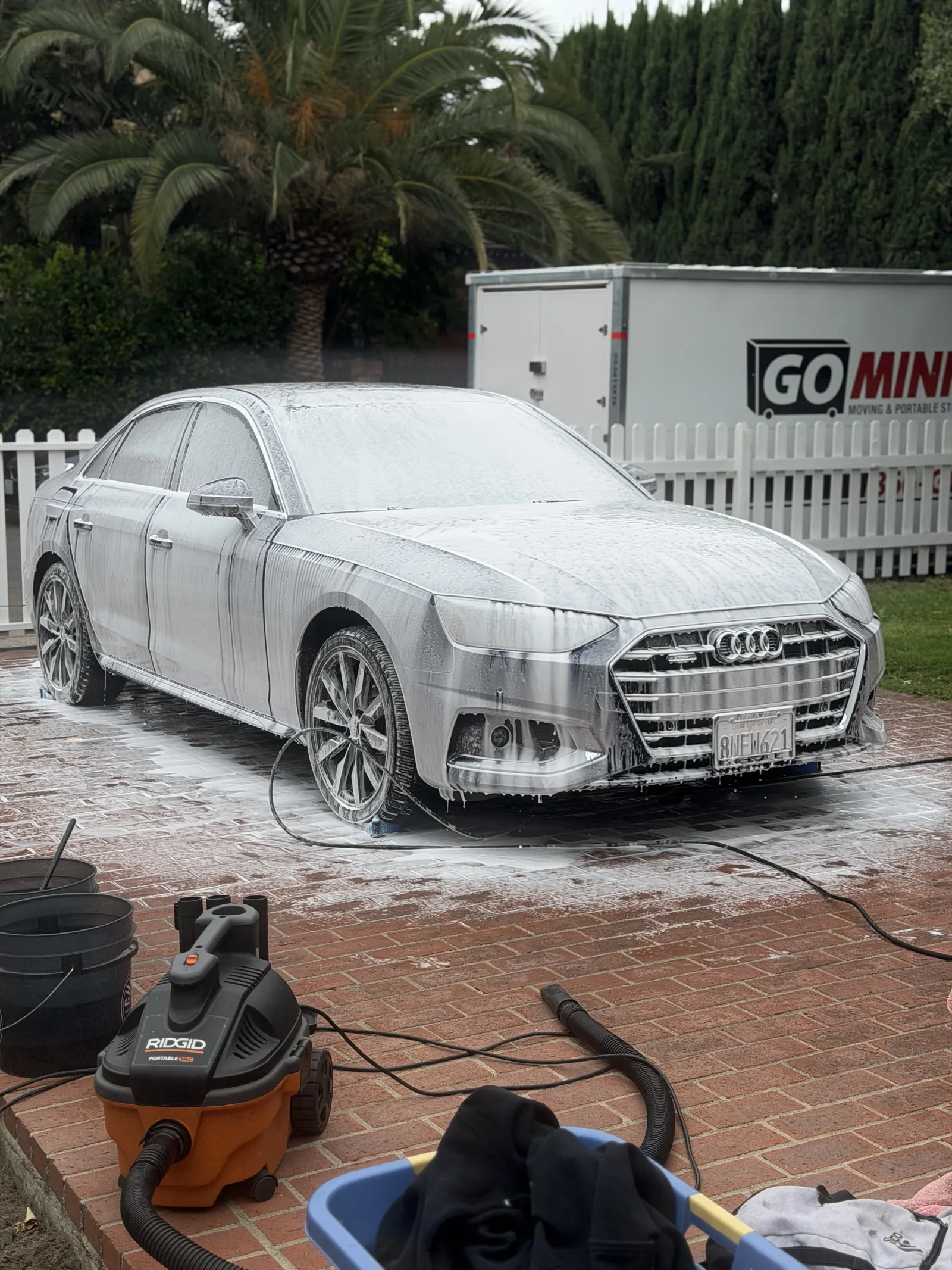 Audi A4 covered in foam with a vacuum and buckets set up on the driveway