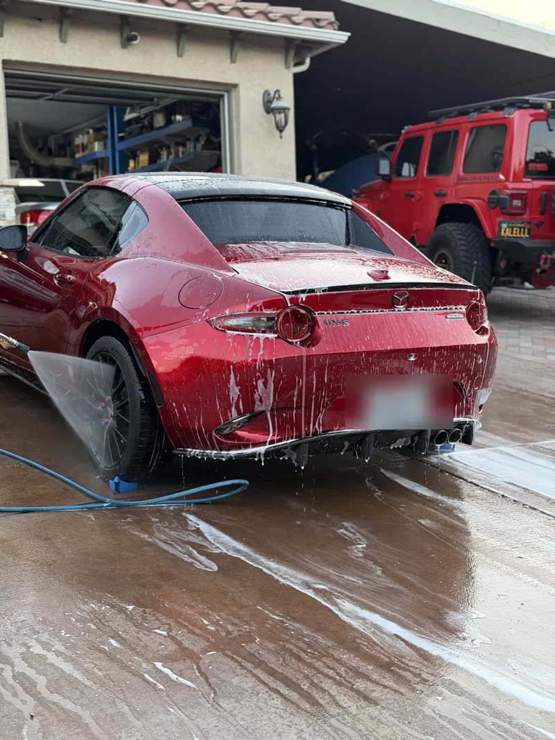 Red Mazda MX-5 covered in foam during a mobile wash